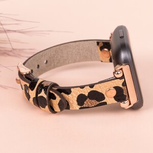 May include: A leopard print watch band with rose gold accents. The band is made of leather and has a buckle closure.