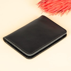 Peut inclure: Un portefeuille en cuir noir avec un bord cousu.