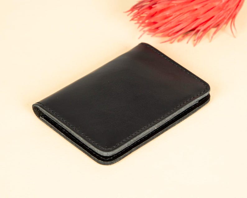 Peut inclure: Un portefeuille en cuir noir avec un bord cousu.