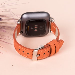 May include: A brown leather watch strap with silver hardware. The strap is designed for a smartwatch with a square face.