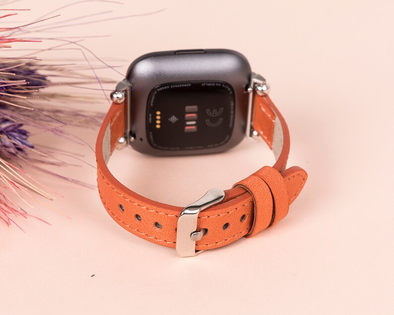 May include: A brown leather watch strap with silver hardware. The strap is designed for a smartwatch with a square face.