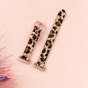 May include: Two leopard print watch bands with gold accents. The bands are made of leather and have a black and brown leopard print pattern.