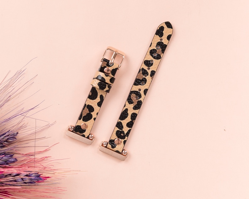 May include: Two leopard print watch bands with gold accents. The bands are made of leather and have a black and brown leopard print pattern.