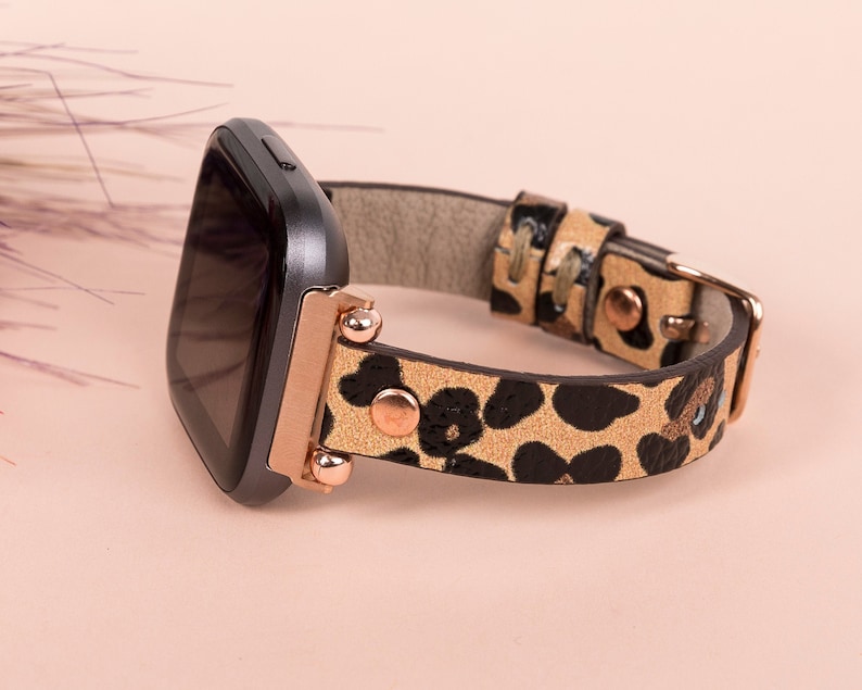 May include: A black smartwatch with a rose gold band featuring a leopard print design.