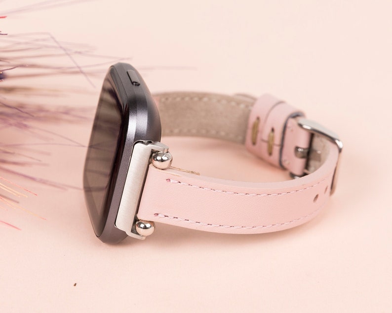 May include: A pink leather watch band with silver accents and a black watch face.