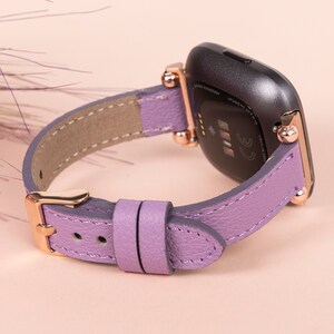 May include: A purple leather watch band with rose gold hardware. The band is designed for a smartwatch with a square face.