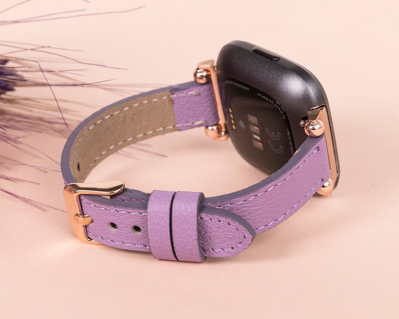 May include: A purple leather watch band with rose gold hardware. The band is designed for a smartwatch with a square face.