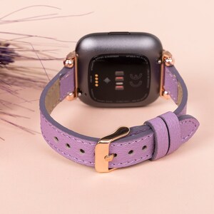 May include: A lavender leather watch band with rose gold hardware. The band is designed for a smartwatch with a square face.