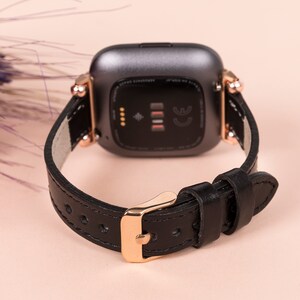 May include: Black leather watch strap with rose gold hardware and a black watch face. The watch face has a small diamond-shaped symbol and the letters CE.