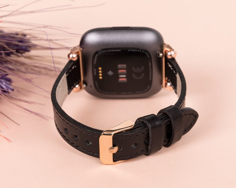 May include: Black leather watch strap with rose gold hardware and a black watch face. The watch face has a small diamond-shaped symbol and the letters CE.