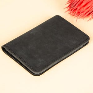 Peut inclure: Un portefeuille en cuir noir avec un bord cousu.