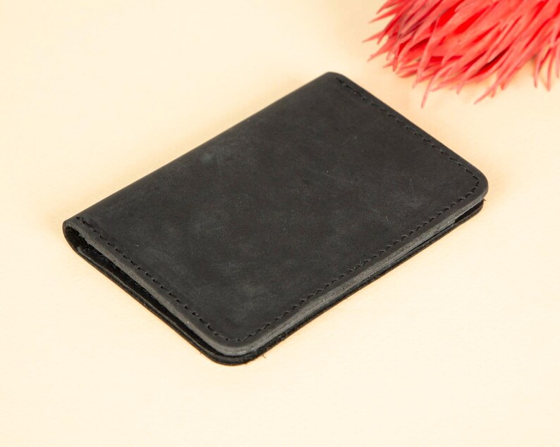 Peut inclure: Un portefeuille en cuir noir avec un bord cousu.