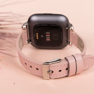 May include: A pink leather watch band with a silver buckle and a black watch face. The watch face has a small screen and the text "CE" on it.
