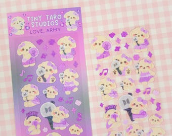 Könnte beinhalten: Eine Blatt mit Aufklebern, die Comic-Hunde mit Glitzerakzenten zeigen. Die Aufkleber befinden sich auf einem lila und rosa Hintergrund mit dem Text "Tiny Taro Studios Love, Army".