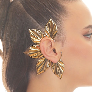 May include: A gold leaf ear cuff with a delicate floral design. The cuff is made of metal and has a textured finish.