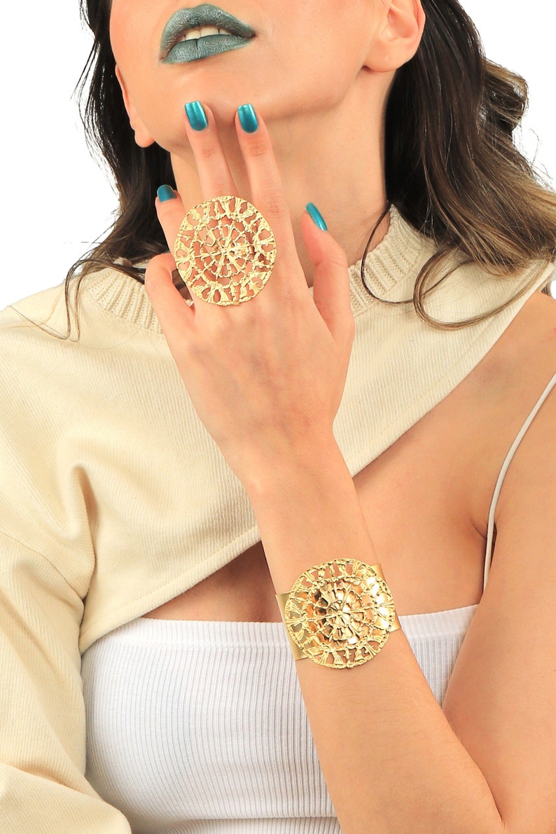 May include: A gold-toned ring and bracelet set with a delicate, intricate, circular design. The jewelry is made of a filigree pattern.