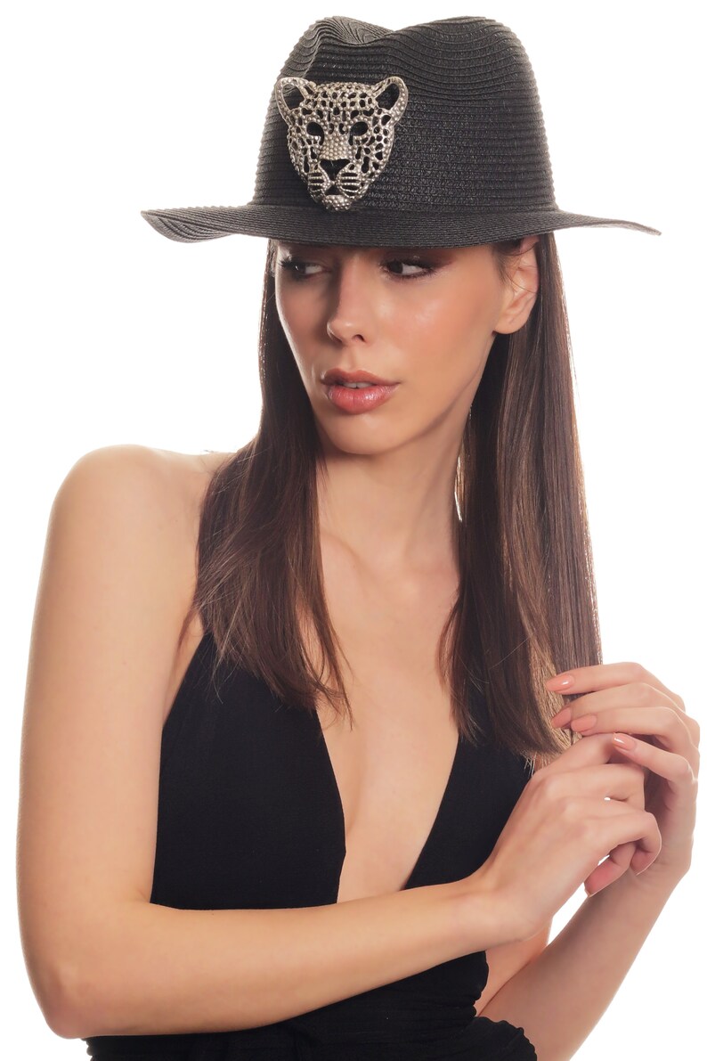 Puede incluir: Un sombrero de paja negro de ala ancha con un dise&ntilde;o de leopardo de pedrer&iacute;a en la parte delantera.