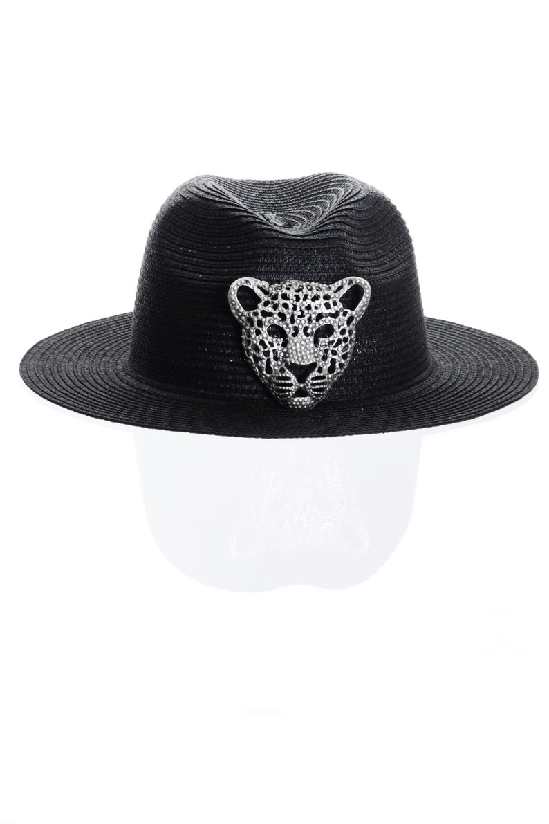 Puede incluir: Un sombrero fedora negro con un dise&ntilde;o de leopardo plateado en la parte delantera.