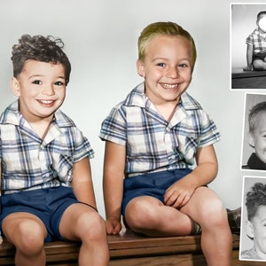 May include: Two young boys wearing matching plaid shirts and blue shorts are sitting on a wooden bench. They are both smiling and looking at the camera.
