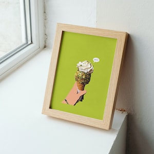 May include: A framed print of a hand holding a pistachio ice cream cone on a green background. The ice cream cone has a white swirl of ice cream and is topped with pistachios. The text "Yum!" is in a speech bubble above the ice cream cone.