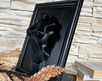 May include: A black framed wall art piece featuring a 3D printed sculpture of a torso. The sculpture is made of a smooth, black material and is displayed against a black background. The frame is made of a dark wood and has a simple, modern design.