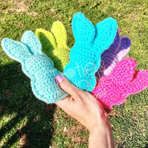 May include: Five crocheted bunny rabbit toys in different colors: light blue, green, purple, pink, and light blue. The toys are made with a soft, textured yarn and have a cute, whimsical design.