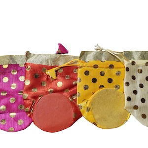 May include: Four small drawstring bags with gold polka dots on a white background. The bags are in pink, red, yellow, and cream.