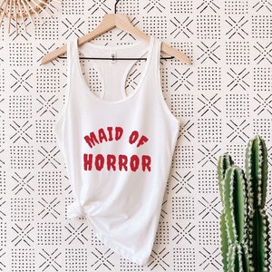 Peut inclure: Un débardeur blanc avec le texte "Maid of Horror" en lettres rouges.