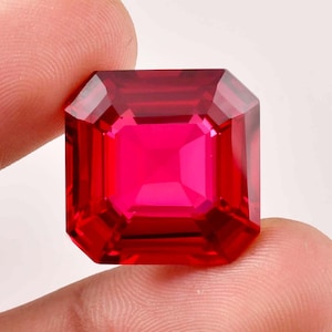 May include: A vibrant red emerald cut gemstone with a square shape.