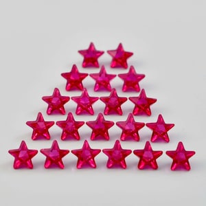 May include: A pyramid-shaped arrangement of twenty pink star-shaped rhinestones.