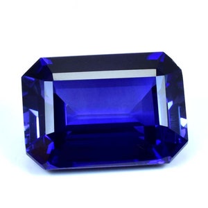 May include: A deep blue gemstone with a rectangular emerald cut. The gemstone is faceted and has a high polish.