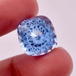 May include: A light blue cushion-cut gemstone with a star-like pattern in the centre.