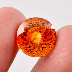 May include: A large, oval-shaped, orange gemstone with a star-shaped pattern in the center.