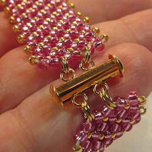 May include: A pink and gold beaded bracelet with a gold toggle clasp.