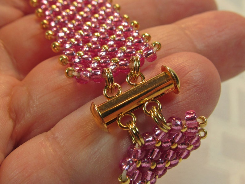 May include: A pink and gold beaded bracelet with a gold toggle clasp.