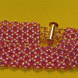 May include: A pink beaded bracelet with a gold clasp. The bracelet is made of small, round beads that are arranged in a pattern.