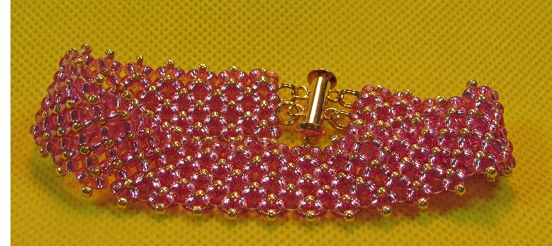 May include: A pink beaded bracelet with a gold clasp. The bracelet is made of small, round beads that are arranged in a pattern.