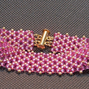 May include: A pink and gold beaded bracelet with a gold clasp.