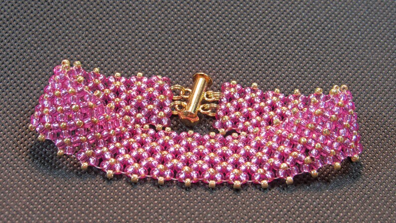 May include: A pink and gold beaded bracelet with a gold clasp.