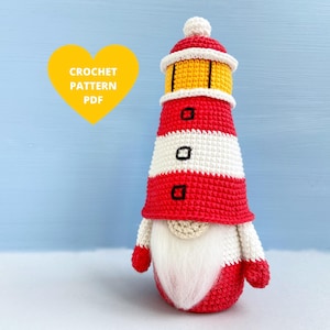 May include: Crocheted lighthouse gnome with a red and white striped hat, a yellow top, and a white beard. The gnome is standing on a white surface. Crochet pattern PDF.