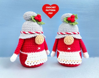 Può includere: Due gnomi all'uncinetto con corpi rossi, grembiuli bianchi e cappelli grigi con accenti di agrifoglio. Gli gnomi sono in piedi su uno sfondo blu. CROCHET PATTERN PDF è scritto in rosso su uno sfondo a forma di cuore.