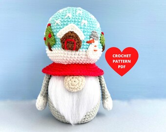 May include: A crocheted gnome with a white beard, gray body, and red hat. The gnome's head is decorated with a blue and white crocheted snow globe with a small snowman and a green Christmas tree.
