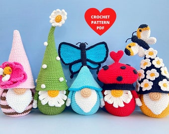 May include: A set of five crocheted gnomes, each with a different spring-themed hat. The gnomes are wearing hats with a butterfly, ladybug, daisy, bee, and flower designs. The gnomes are all standing on a blue surface. Crochet Pattern PDF.