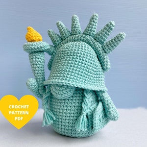 Op de afbeelding: Haakpatroon PDF voor een tealblauwe gehaakte Vrijheidsbeeld amigurumi pop. De pop heeft een gele fakkel en een kroon.