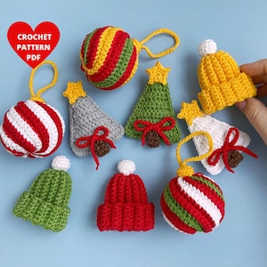 May include: A collection of nine crocheted Christmas decorations, including a striped bauble, a tree, a hat, and a star. The decorations are in various colours, including red, green, white, and yellow.