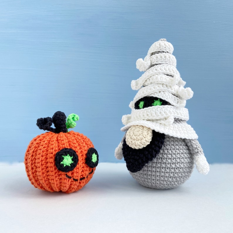Pu&ograve; includere: Una zucca arancione all'uncinetto con occhi verdi e un gnomo mummia all'uncinetto bianco con occhi neri.