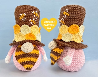 May include: Two crocheted gnome ornaments with brown hats and pink bodies. The hats are decorated with yellow and white crocheted honeycomb patterns and brown bees. The gnomes have brown and yellow striped beards.