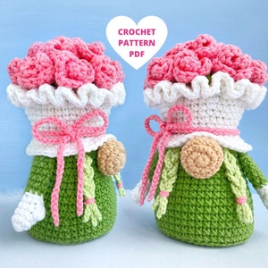 May include: Two crocheted gnomes with pink flower bouquets on their heads. The gnomes are wearing white hats with pink bows and green dresses. They have white mittens and green braids.