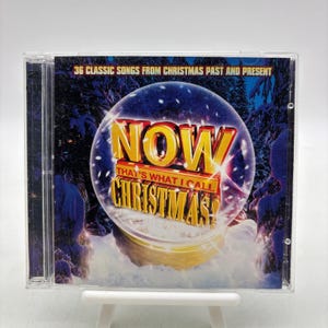 May include: A Now That's What I Call Christmas! music CD in a clear plastic jewel case. The cover features a snow globe with gold text reading Now That's What I Call Christmas! against a snowy, dark blue forest background.