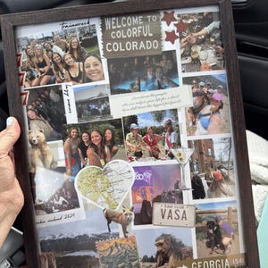 May include: A framed collage with a dark brown wooden frame. The collage includes various photos, stickers, and text elements, including "WELCOME TO COLORFUL COLORADO" and "GEORGIA 1541 MILES". The photos depict people and landscapes.